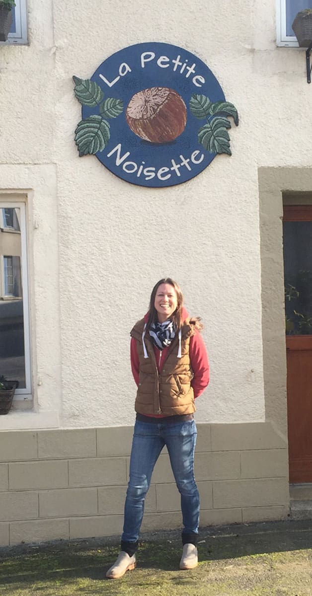 Artist Sarah Berry standing in front of restaurant mosaic sign