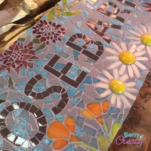 close up of mosaic sign with blue background and flowers
