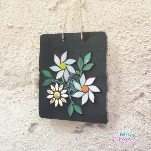 white flowers on slate hanging on stone wall with twine