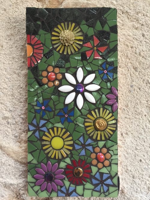 mosaic with lots of birght colored flowers hanging on a wall