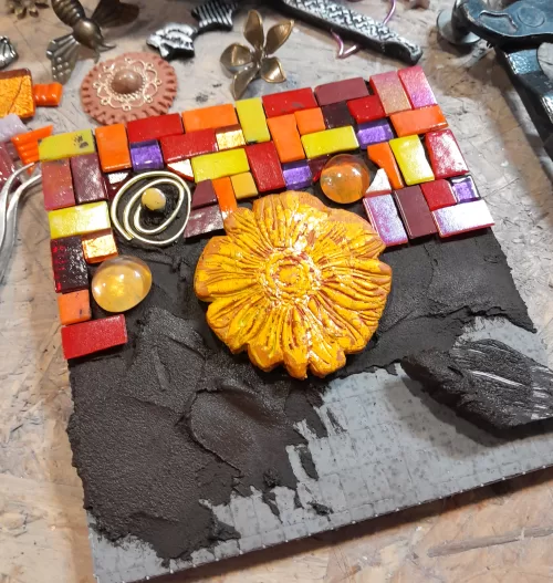 square mosaic in progress being made using red, orange and yellow glass tiles, and tile adhesive - no grout method